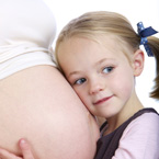 Young girl listening to pregnant mothers belly